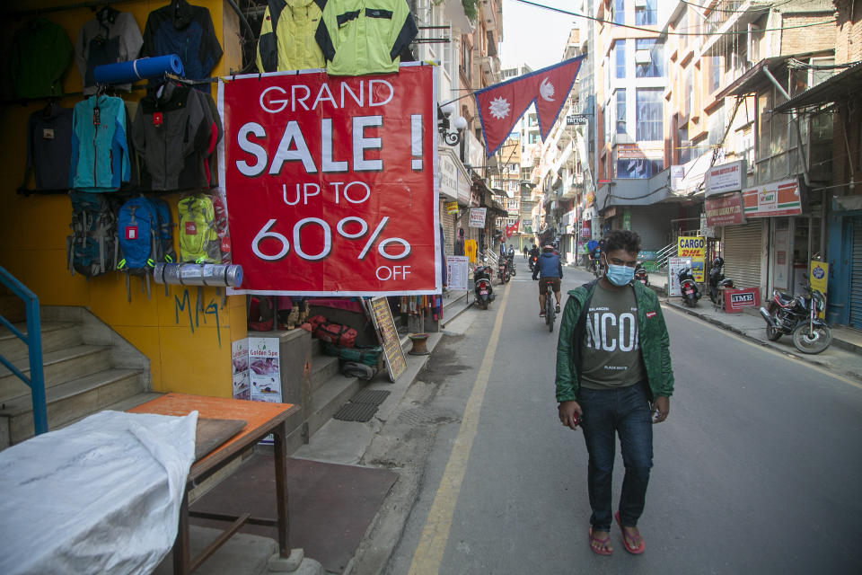 A Nepalese man walks past a trekking gear store at Thamel, a touristic hub in Kathmandu, Nepal, Monday, Nov. 2, 2020. Nepal has reopened its peaks and trails for foreign adventurers in hopes of providing much needed income for hundreds of thousands of guides, porters and workers who have been unemployed for months because of the pandemic. (AP Photo/Niranjan Shrestha)