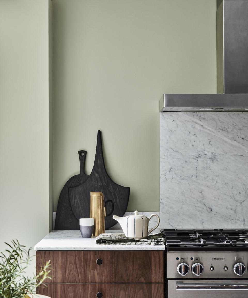 A light green kitchen with a black extractor fan