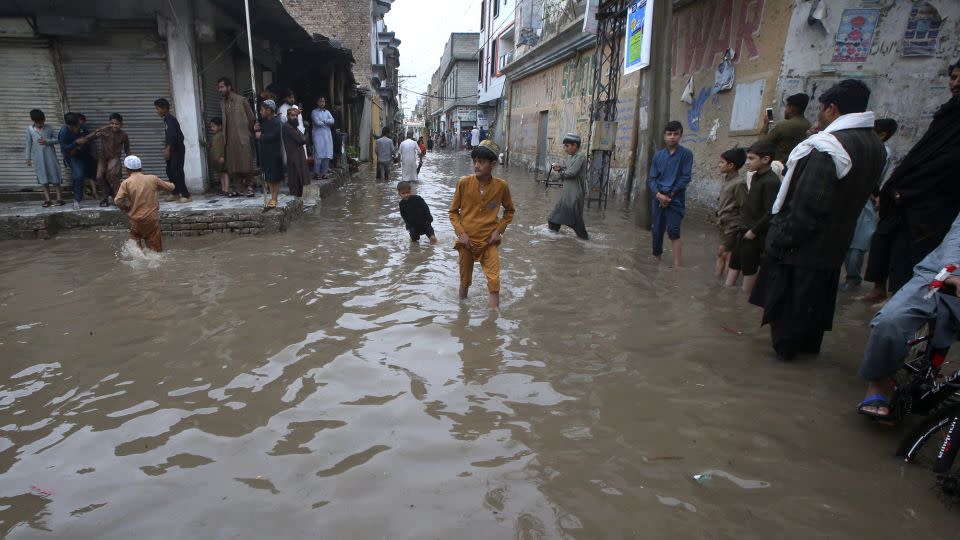 People wade through a street flooded by heavy rain in Peshawar, Pakistan on April 15, 2024. - Muhammad Sajjad/AP