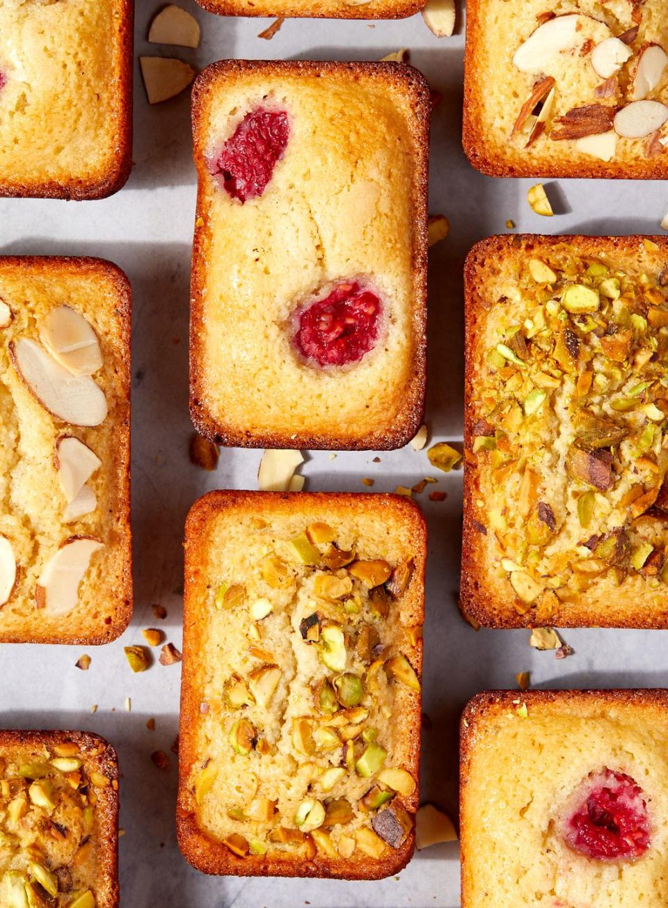 financier cakes with topped with raspberries, pistachios, and almonds