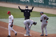First base umpire Lee Ki-joong wearing a mask and gloves as a precaution against the new coronavirus calls during a baseball game between Hanwha Eagles and SK Wyverns in Incheon, South Korea, Tuesday, May 5, 2020. With umpires fitted with masks and cheerleaders dancing beneath vast rows of empty seats, a new baseball season got underway in South Korea following a weeks-long delay because of the coronavirus pandemic.(AP Photo/Lee Jin-man)