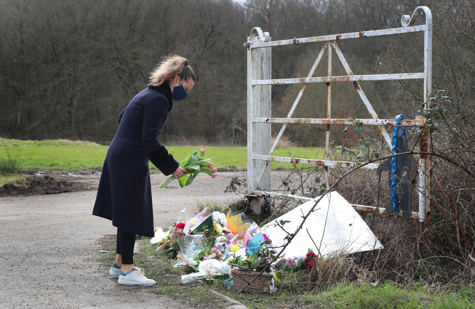 A lady lays flowers near the scene in Ashford, Kent, after a body found hidden in nearby woodland was identified as that of 33-year-old Sarah Everard. Serving police constable Wayne Couzens, 48, appeared in court on Saturday charged with kidnapping and murdering the 33-year-old marketing executive, who went missing while walking home from a friend's flat in south London on March 3. Picture date: Sunday March 14, 2021.