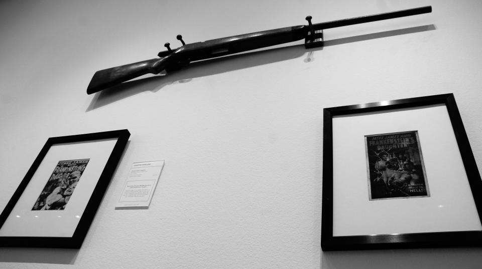 A rifle is positioned above the improbable meeting of Jesse James and Frankenstein's offspring in "Frankenstein's Daughter: A Match Made in Hell" displayed at Jody Klotz Fine Art. Imagine if the famous outlaw hid from Marshall MacPhee in the baron's castle? It was a 1966 movie.