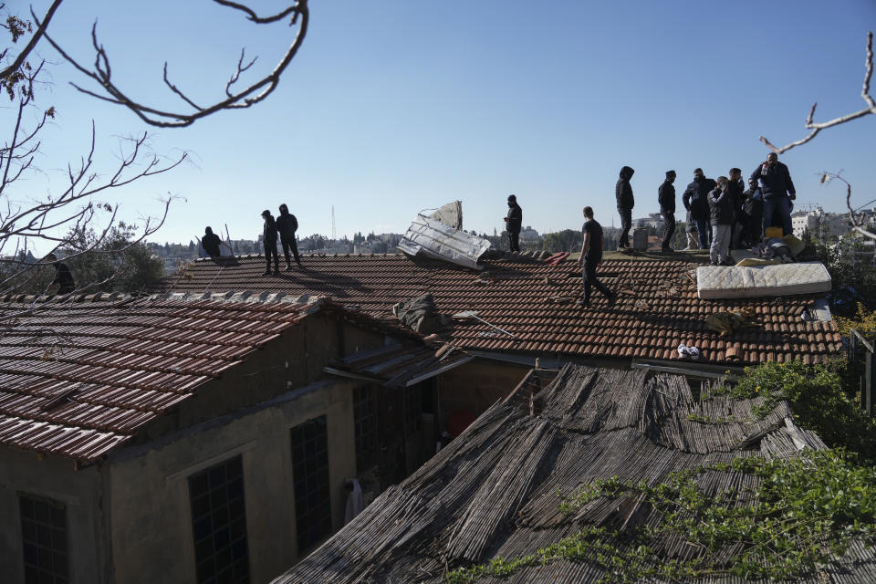 Palestinian men stand on the roof of a house with gas tanks and threaten to set them on fire should the Jerusalem municipality evict the family, in the flashpoint east Jerusalem neighborhood of Sheikh Jarrah, Monday, Jan. 17, 2022. City Hall and the police issued a joint statement saying a court ordered the family to vacate the property a year ago. (AP Photo/Mahmoud Illean)