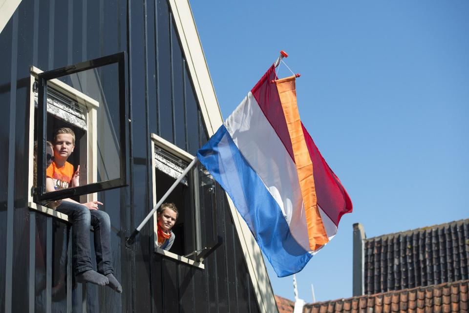 People look out of windows to get a glimpse of Netherlands' King Willem Alexander and Queen Maxima during King's Day in De Rijp, 36 kilometers (22 miles) north of Amsterdam, Netherlands, Saturday, April 26, 2014. The Dutch marked King's Day on Saturday, a national holiday held in honor of the newly installed monarch, King Willem Alexander. King's Day replaces the traditional Queen's Day. (AP Photo/Patrick Post)