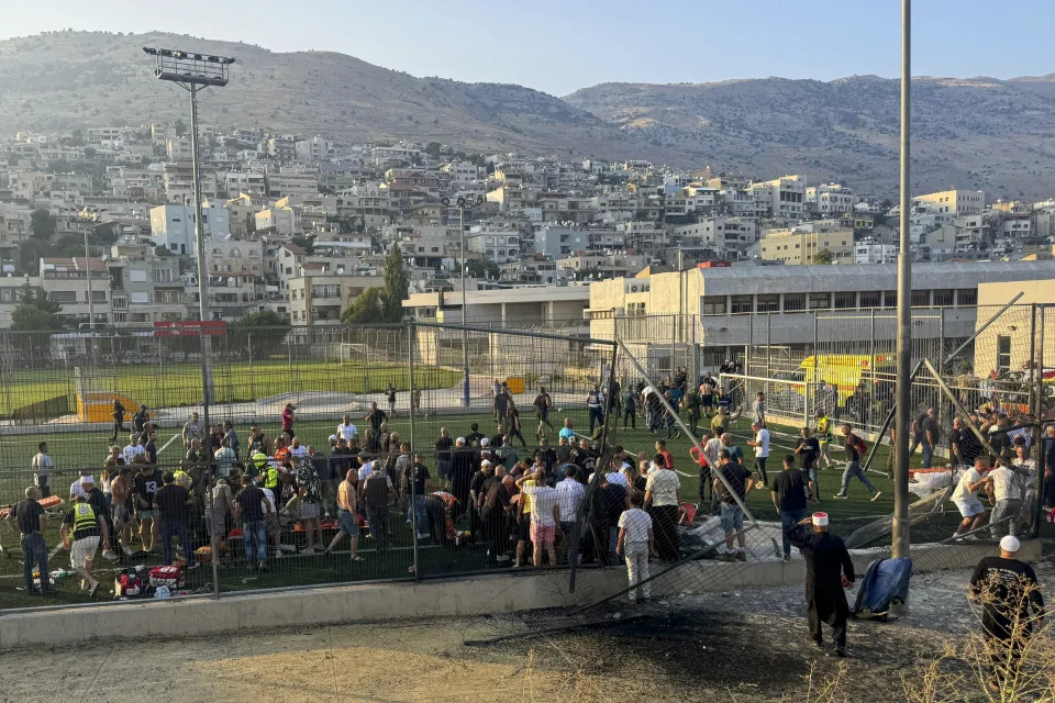 Residence and paramedics rush to help children moments after a rocket attack hit a soccer field in the Druze town of Majdal Shams in the Israeli-controlled Golan of Heights, Saturday, July 27, 2024. (AP Photo/Hassan Shams)