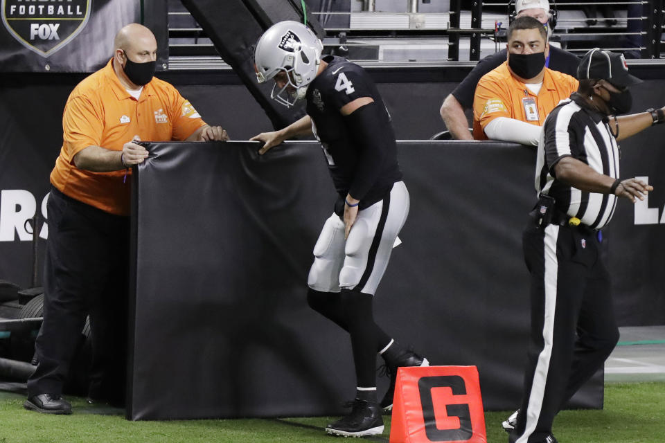 Las Vegas Raiders quarterback Derek Carr (4) limps on the sidelines after a play against the Los Angeles Chargers during the first half of an NFL football game, Thursday, Dec. 17, 2020, in Las Vegas. (AP Photo/Isaac Brekken)
