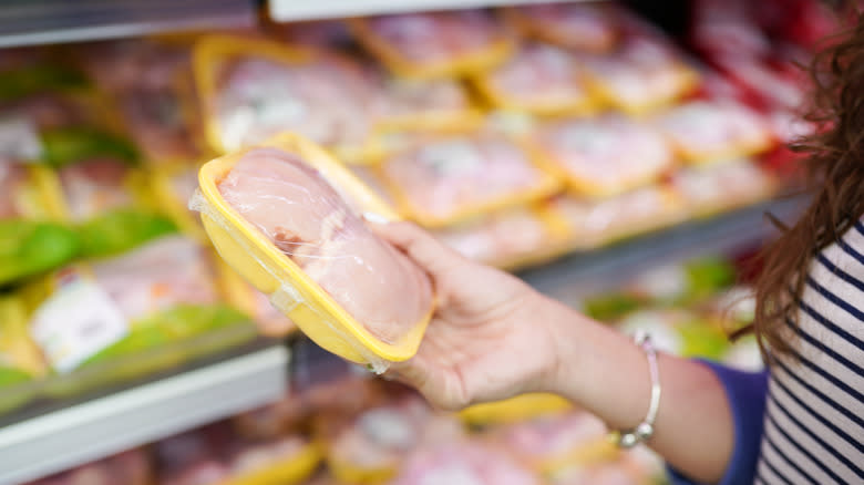 Woman holding pack of chicken in store