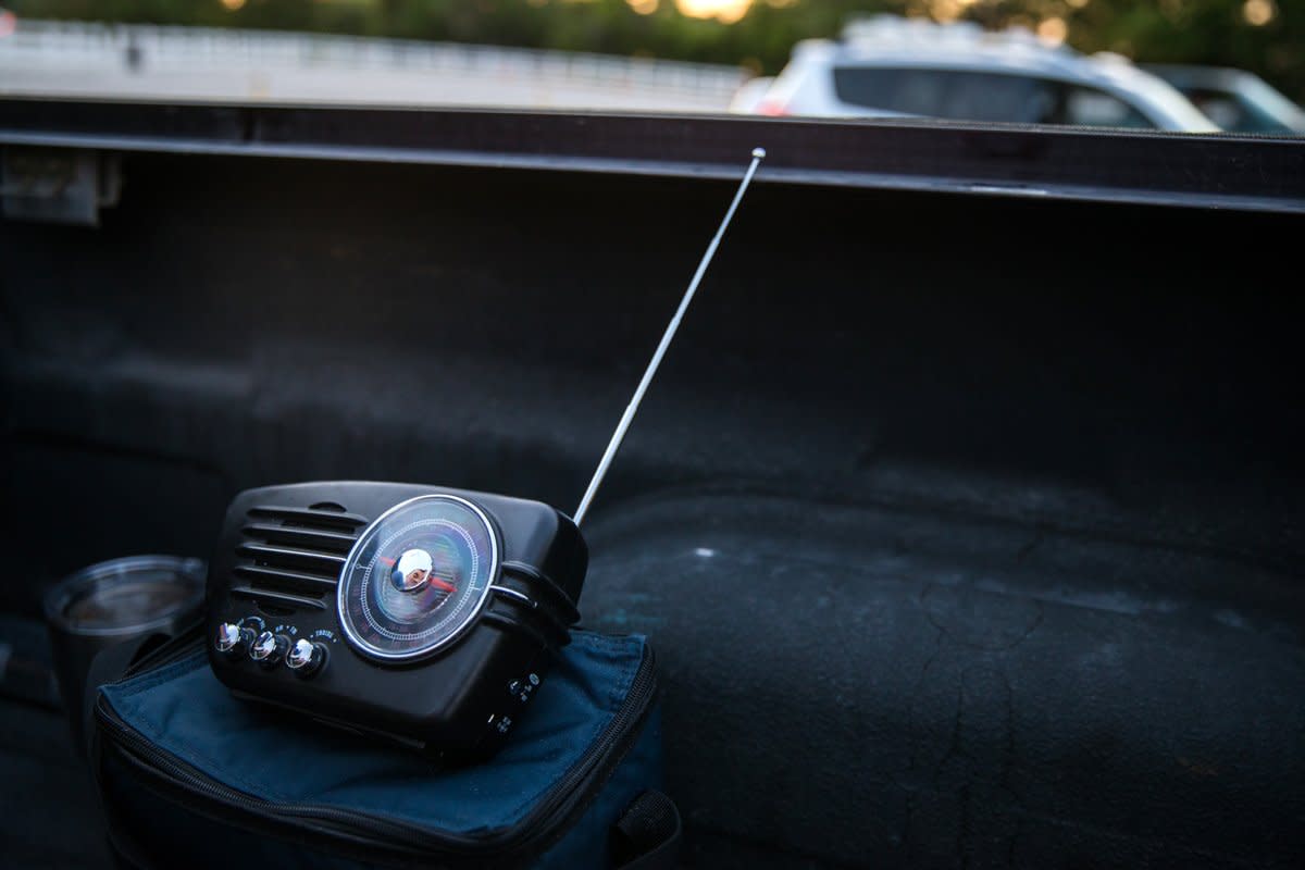 A battery-operated radio sits on the dashboard of someone's car. 