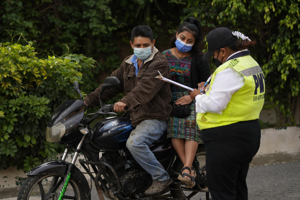 People are registered by a transit agent at a checkpoint on the second day of a four-day lockdown, decreed by local authorities to help curb the spread of COVID-19 in the Kaqchikel Indigenous town of San Martin Jilotepeque, Guatemala, Friday, July 9, 2021. On Thursday, Guatemala announced its highest number of infections since the pandemic began, with 3,000 infected in a single day. (AP Photo/Moises Castillo)