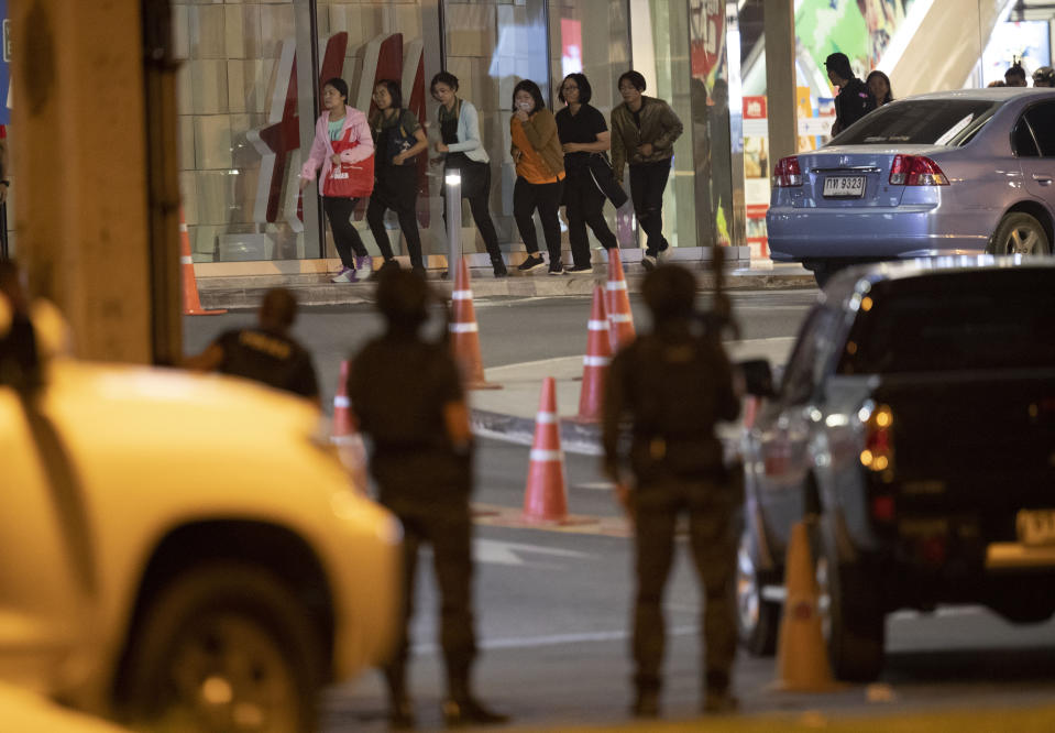 People who were able to get out of Terminal 21 Korat mall walk outside the building in Nakhon Ratchasima, Thailand on Sunday, Feb. 9, 2020. A soldier who holed up in a popular shopping mall in northeastern Thailand shot multiple people on Saturday, killing at least 20 and injuring 31 others, officials said. (AP Photo/Sakchai Lalitkanjanakul)