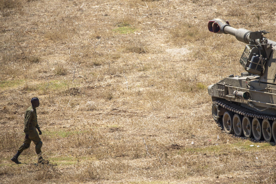 An Israeli soldier walks towards a mobile artillery piece near the border with Lebanon, northern Israel, Wednesday, Aug. 26, 2020. The Israeli military said attack helicopters have struck observation posts of the militant Hezbollah group along the Lebanon border after shots were fired at Israeli troops. Israel has been bracing for a possible attack by Hezbollah since an Israeli airstrike killed a Hezbollah fighter in neighboring Syria last month. (AP Photo/Ariel Schalit)