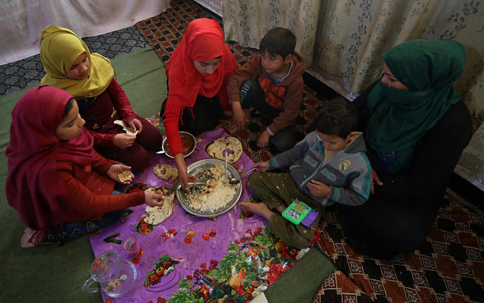 In this March 18, 2019 photo, Um Yusuf, a widow of an Islamic State group militant, and her children have lunch, in Mosul, Iraq. Thousands of Iraqi families face crushing social and legal discrimination -- all because of the choices their male relatives made under the Islamic State group’s rule. Um Yusuf and her seven children were left to shoulder the stigma of her husband's IS affiliation. She cannot get social assistance, and her teenage son Omar is being turned away from jobs. (AP Photo/Farid Abdulwahed)