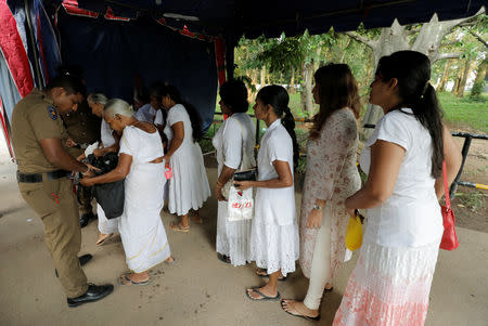 Police officers search the bags of the worshipers at an entrance of the Kelaniya Buddhist temple during Vesak Day, commemorating the birth, enlightenment and death of Buddha, in Colombo, Sri Lanka May 18, 2019. REUTERS/Dinuka Liyanawatte