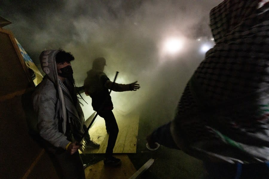 Pro-Palestinian demonstrators engulfed in tear gas regroup and rebuild the barricade surrounding the encampment set up on the campus of the University of California Los Angeles (UCLA) as clashes erupt with counter protesters, in Los Angeles on May 1, 2024. Clashes broke out on May 1, 2024 around pro-Palestinian demonstrations at the University of California, Los Angeles, as universities around the United States struggle to contain similar protests on dozens of campuses. (Photo by ETIENNE LAURENT / AFP) (Photo by ETIENNE LAURENT/AFP via Getty Images)