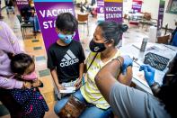 Myat Myat, of Pittsburgh, Pa. second from right, receives a second dose of the COVID-19 vaccine, as her children Theinlar Soesan, 11, Lawon Kyai, 3, and Naylen Yeng, 8, look on, at a clinic organized by Age-Friendly Greater Pittsburgh, Free the Vaccine and Lively Pittsburgh to serve the Bhutanese community, Saturday, May 15, 2021, at Whitehall Presbyterian Church in Whitehall, Pa. The clinic featured a pop-up experience including Bhutanese music, samosas and chai, and a Polaroid photo opportunity to encourage people to get vaccinated. (Alexandra Wimley/Pittsburgh Post-Gazette via AP)