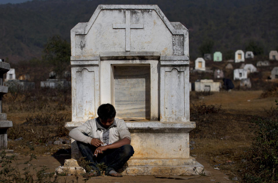 In this Jan 28, 2014 photo, an addict leans on a white tombstone as he shoots up heroin at a cemetery in Nampatka village, northeastern Shan State, Myanmar. More than 100 heroin and opium addicts descend on the graveyard every morning, rolling up their sleeves for quick fixes or drawing at pipes with no fear of reprisals. (AP Photo/Gemunu Amarasinghe)