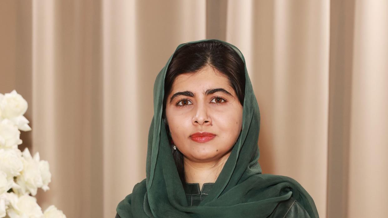 malala yousafzai looks directly at the camera, she wears a green outfit and head scarf