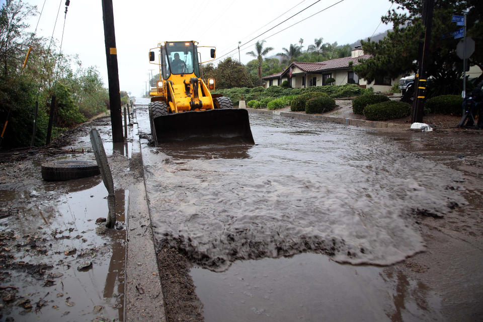 Glendora city workers clear mud and debris from the hills, in Glendora, Calif. on Friday, Feb. 28, 2014. The first wave of a powerful Pacific storm spread rain and snow early Friday through much of California, where communities endangered by a wildfire just weeks ago now faced the threat of mud and debris flows. (AP Photo/Nick Ut)