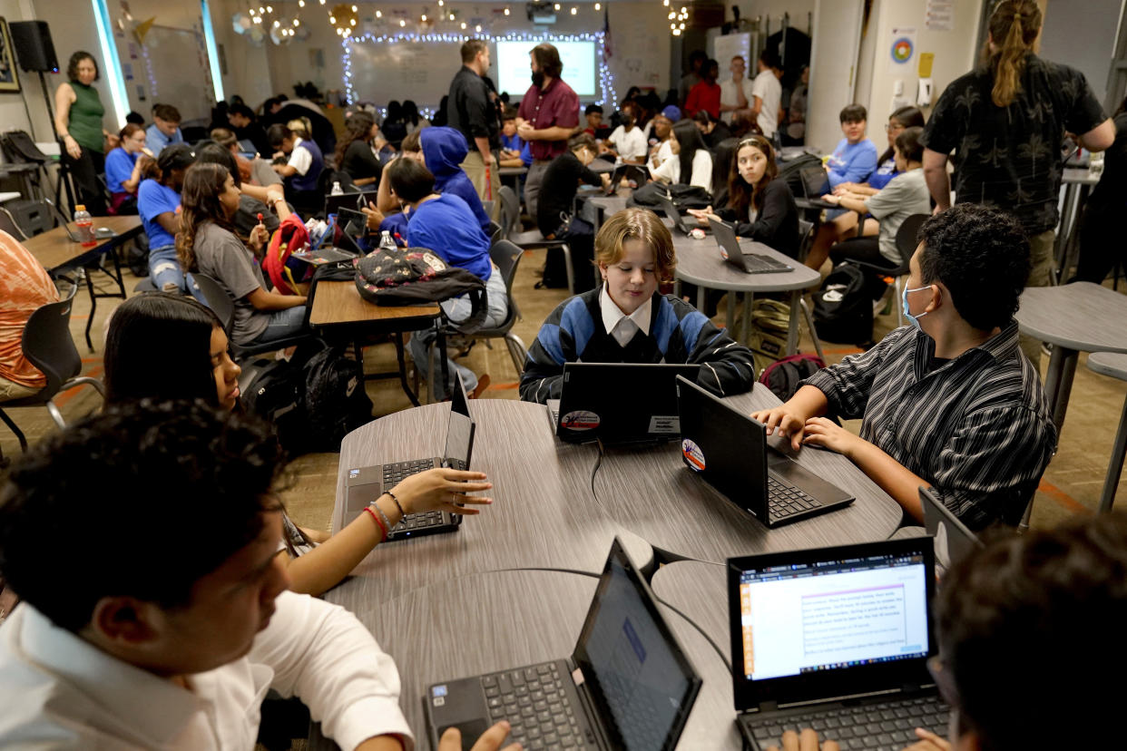 Westwood High School English teacher Jeff Hall, top center, monitors his class, Tuesday, Oct. 18, 2022 in Mesa, Ariz. Like many school districts across the country, Mesa has a teacher shortage due in part due to low morale and declining interest in the profession. Five years ago, Mesa allowed Westwood to pilot a program to make it easier for the district to fill staffing gaps, grant educators greater agency over their work and make teaching a more attractive career. The model, known as team teaching, allows teachers to combine classes and grades rotating between big group instruction, one-on-one interventions, small study groups or whatever the team agrees is a priority each day. (AP Photo/Matt York)