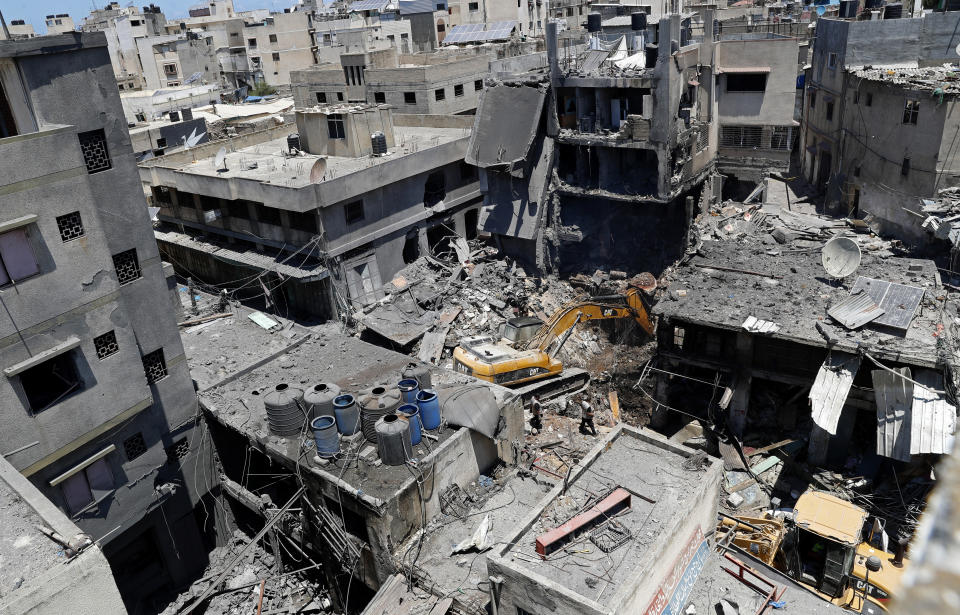 Palestinian security officers watch as a mechanical digger works to remove rubble at the site of an explosion in the Al-Zawiya market, in Gaza City, Gaza, Thursday, July 22, 2021. At least one person was killed and some 10 injured Thursday when the explosion tore through a house in a popular market, the interior ministry said. (AP Photo/Adel Hana)