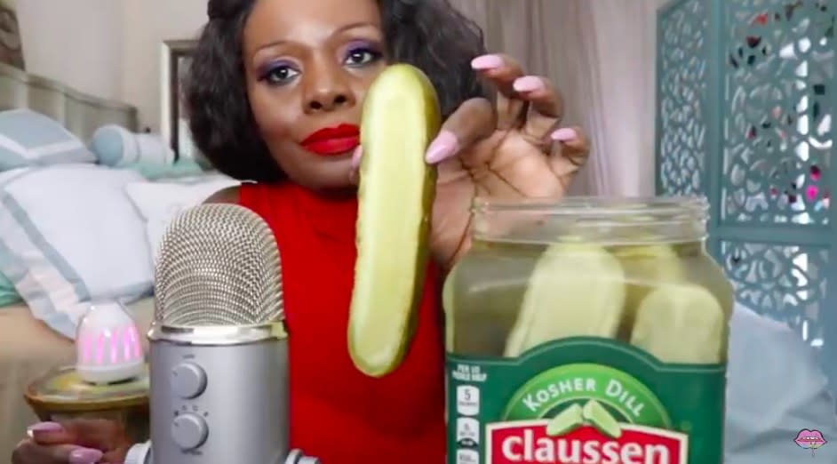 ASMRTheChew pickle eating video. She is in her bedroom showing one pickle from a big jar of pickles