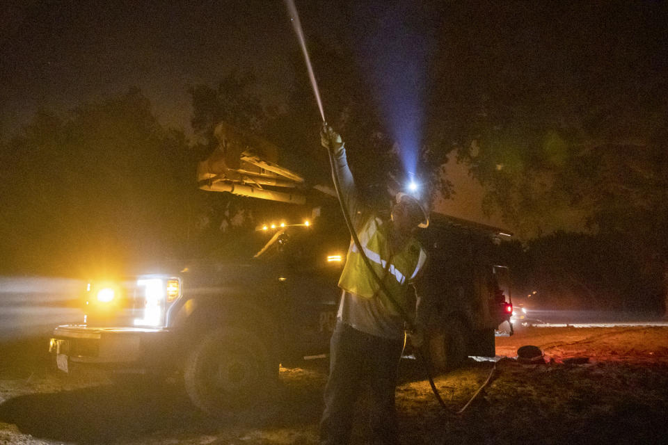 FILE - A Pacific Gas & Electric employee sprays water on a burning telephone pole at the Zogg Fire near Ono, Calif., on Sept. 28, 2020. A judge ruled on Wednesday, Feb. 1, 2023, that Pacific Gas & Electric must face trial for involuntary manslaughter over its role in the 2020 wildfire in Northern California that killed four people. (AP Photo/Ethan Swope, File)