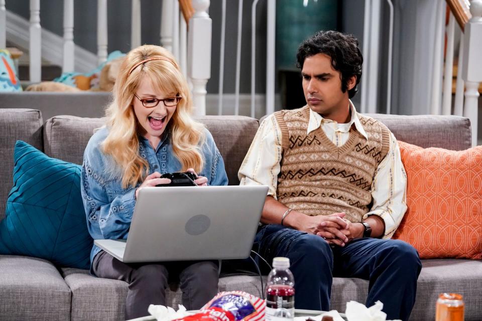 a man and a woman sitting on a couch with a laptop