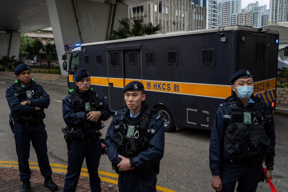 Police officers stand guard as an armored prison van carrying Jimmy Lai leaves West Kowloon Law Courts (AP)
