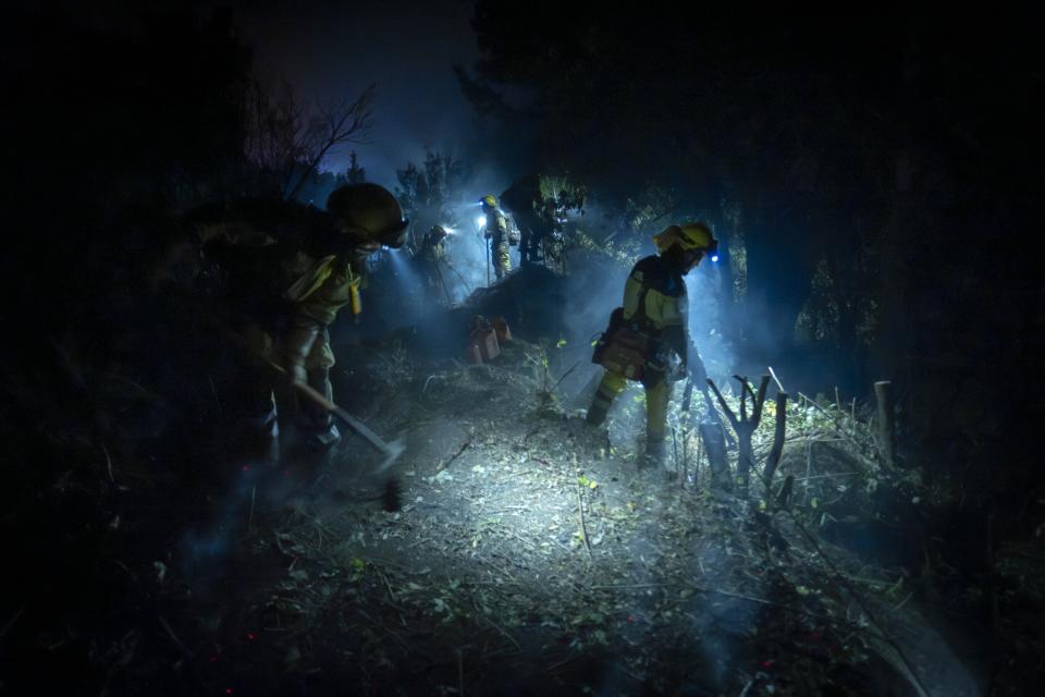 Emergency crews and firefighters work to extinguish the fire advancing through the forest near the town of El Rosario in Tenerife, Canary Islands, Spain on Aug. 18, 2023. (AP Photo/Arturo Rodriguez)