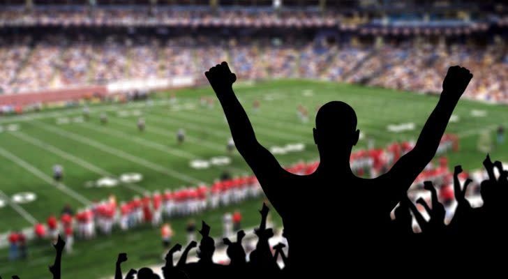 A silhouette of a fan cheering with arms raised at an NFL game.