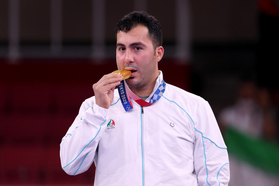 Sajad Ganjzadeh of Team Iran bites his gold medal in celebration