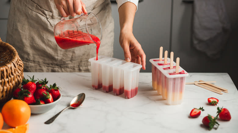 Person pouring fruit into popsicle mold