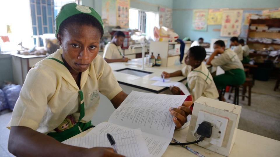 A girl in a classroom writing in a book