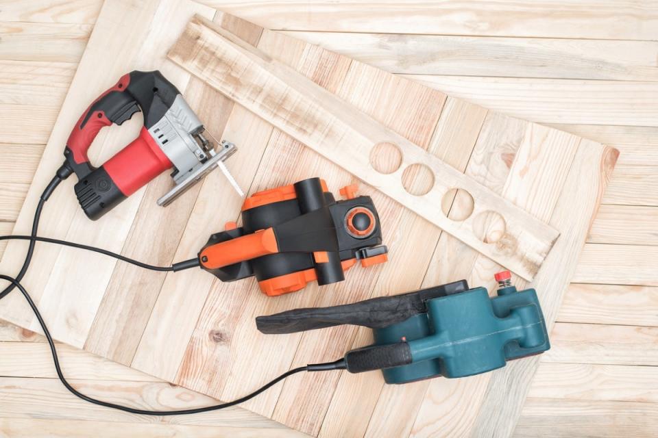 Three power tools resting on plywood