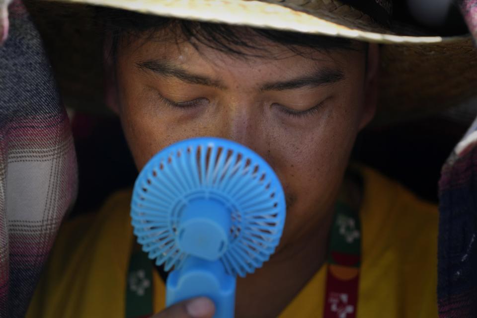 FILE - A World Youth Day volunteer uses a small fan to cool off from the intense heat, as he waits ahead of the Pope Francis arrival at Passeio Marítimo in Algés, just outside Lisbon, Aug. 6, 2023. Six young people from Portugal are arguing on Wednesday, Sept. 27, that governments across Europe aren't doing enough to protect people from the harms of climate change at the European Court of Human Rights. (AP Photo/Armando Franca, File)