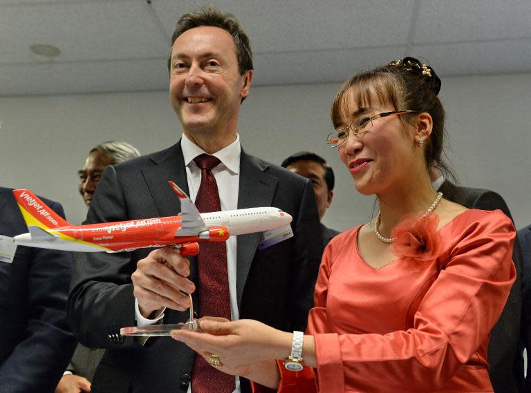 Fabrice Bregier (L), President and CEO of Airbus, presents an Airbus model to Nguywen Thi Phuang Thao, CEO of VietJetAir, after a signing ceremony in Singapore on February 11, 2014