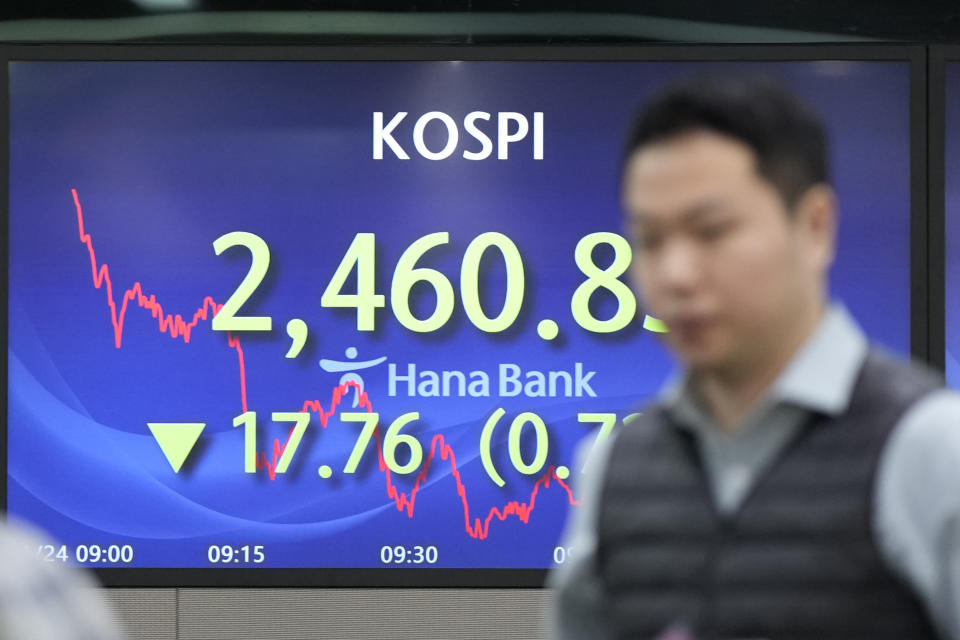 A currency trader walks by the screens showing the Korea Composite Stock Price Index (KOSPI) at a foreign exchange dealing room in Seoul, South Korea, Wednesday, Jan. 24, 2024. Asian shares are mixed after Japan reported its exports jumped nearly 10% in December over a year earlier. But shares in Tokyo fell nearly 1% after a recent strong rally as speculation revived over a shift away from longstanding lax monetary policy by the Bank of Japan. (AP Photo/Lee Jin-man)