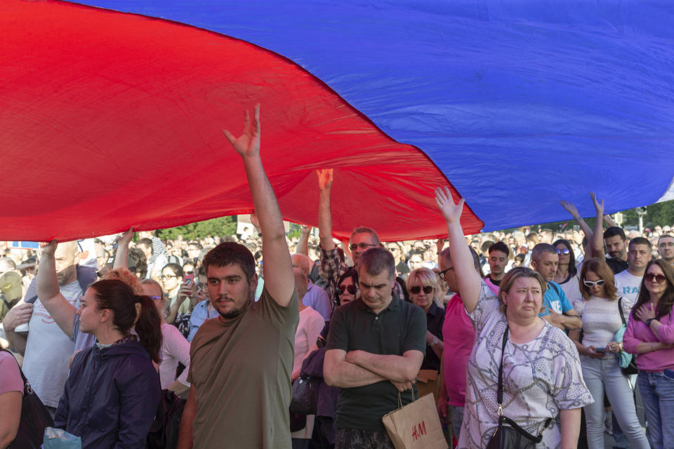 People hold up a giant Serbian flag during a protest in Belgrade, Serbia, Saturday, June 3, 2023. Tens of thousands of people rallied in Serbia's capital on Saturday in protest of the government's handling of a crisis after two mass shootings in the Balkan country. (AP Photo/Marko Drobnjakovic)