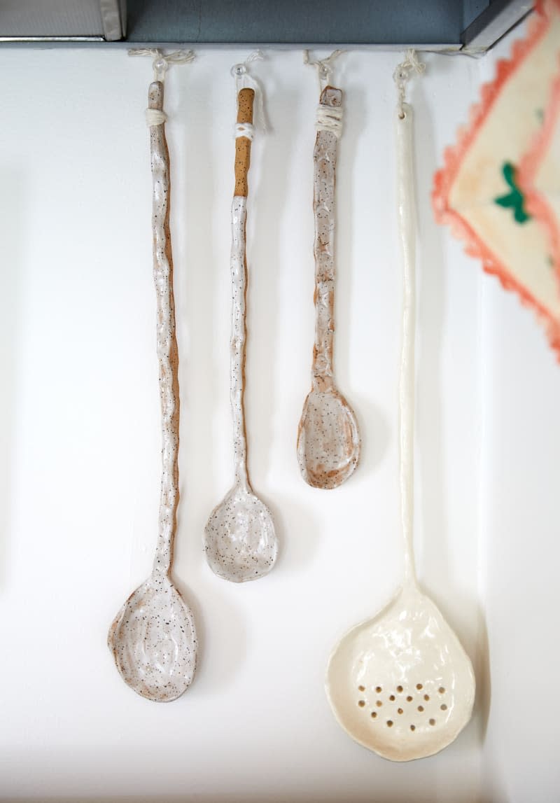Decorated cooking spoons hung in a white-walled kitchen.