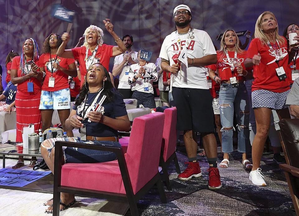 Venus Jewett, back left, mother of Olympic runner Isaiah Jewett, watches her son compete in the 800-meter race and reacts as as Isaiah failed to make the finals as she joins other family and friends of Olympic athletes watching the televised action live at the Olympic Family & Friends Experience at the Loews Sapphire Falls Resort at Universal Orlando in Orlando, Fla., Friday, July 30, 2021. Parents, siblings, friends and former teammates crowd into the ballroom at the resort daily to watch the Summer Games and bond with others in a similar situation, all of them unable to be in Tokyo to root on their loved ones competing for gold because of the coronavirus pandemic. (Stephen M. Dowell/Orlando Sentinel via AP)