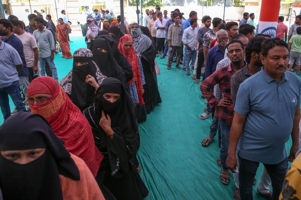 Indian voters wait outside a polling station during the third phase of the election in Ahmedabad, Gujarat (EPA)