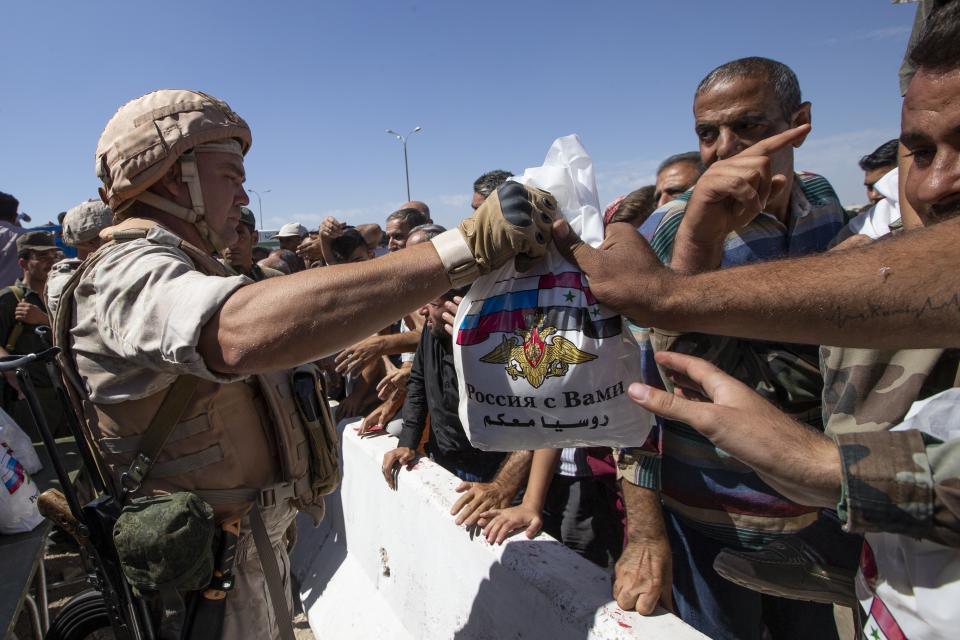 FILE - Russian soldiers distribute food and other supplies to residents of the Syrian town of Khan Sheikhoun, Syria, Sept. 25, 2019. Political observers say Russia’s brazen Syria intervention emboldened Putin, giving him a renewed Middle East foothold and helped pave the way for his current attack on Ukraine. (AP Photo/Alexander Zemlianichenko, File)