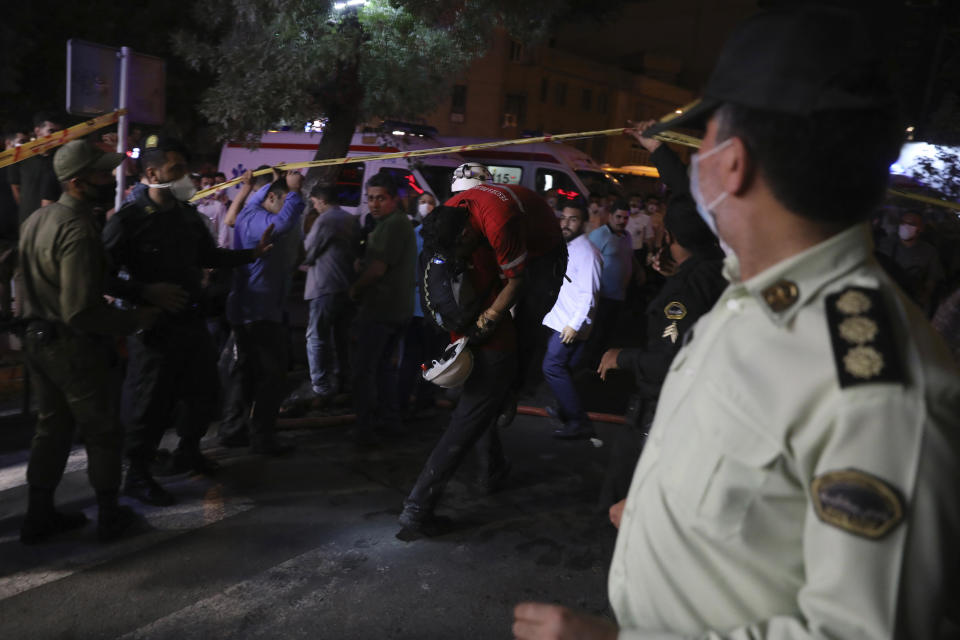 A rescue worker evacuates his colleague as he is overcome by smoke from the explosion of the Sina Athar Clinic in Tehran, Iran, early Wednesday, July 1, 2020. Iranian state TV says an explosion from a gas leak in a medical clinic in northern Tehran has killed multiple people. (AP Photo/Vahid Salemi)