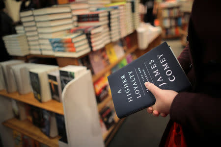 A woman holds a copy of former FBI director James Comey's book "A Higher Loyalty" at Kramerbooks book store in Washington D.C., U.S. April 17, 2018. REUTERS/Carlos Barria/Files