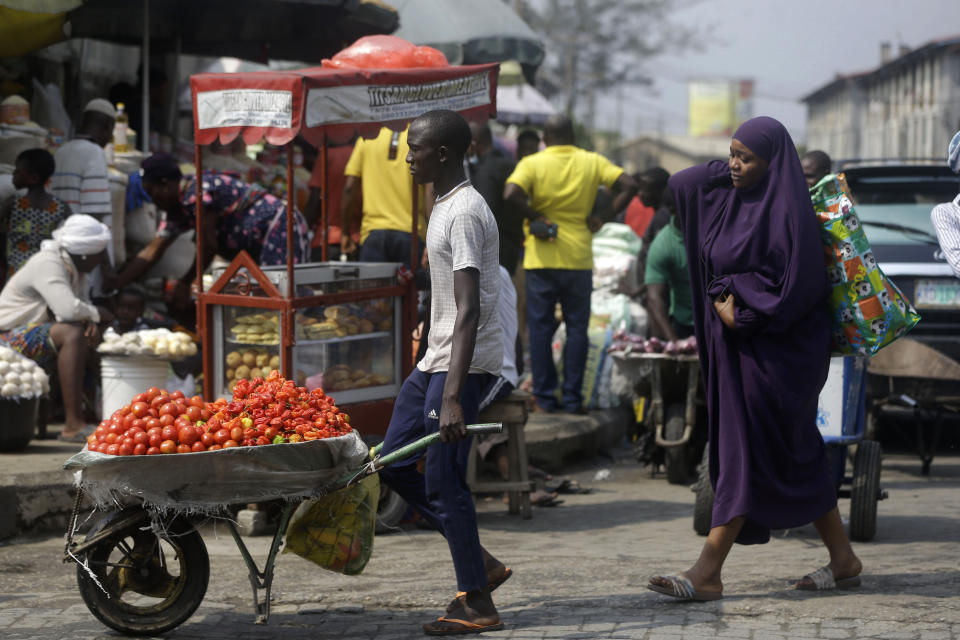 FILE - In this Dec. 24, 2020, file photo, people walk in a market in Lagos, Nigeria. A survey of people aged 18-24 in 15 countries has found that many Africans are battling the economic downturns caused by the COVID-19 pandemic, losing jobs and seeing their education disrupted. Some of them turn to selling farm produce or other goods on the street. (AP Photo/Sunday Alamba, File)