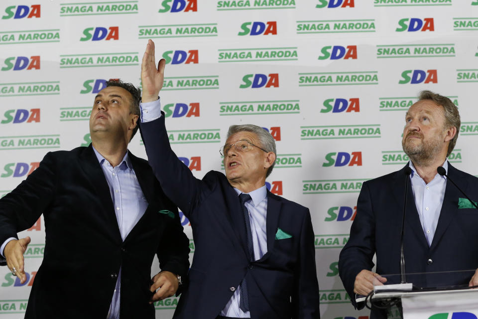 Candidate of Party for Democratic Action Sefket Dzaferovic, center, Asim Sarajlic, left, and Bakir Izetbegovic gesture as he talks to workers who operate fireworks during press conference celebrating unofficial results of election in Sarajevo, Bosnia, Monday, Oct. 8, 2018. (AP Photo/Amel Emric)