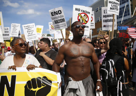 Demonstrators hold placards during a march by various groups, including "Black Lives Matter" and "Shut Down Trump and the RNC". REUTERS/Shannon Stapleton