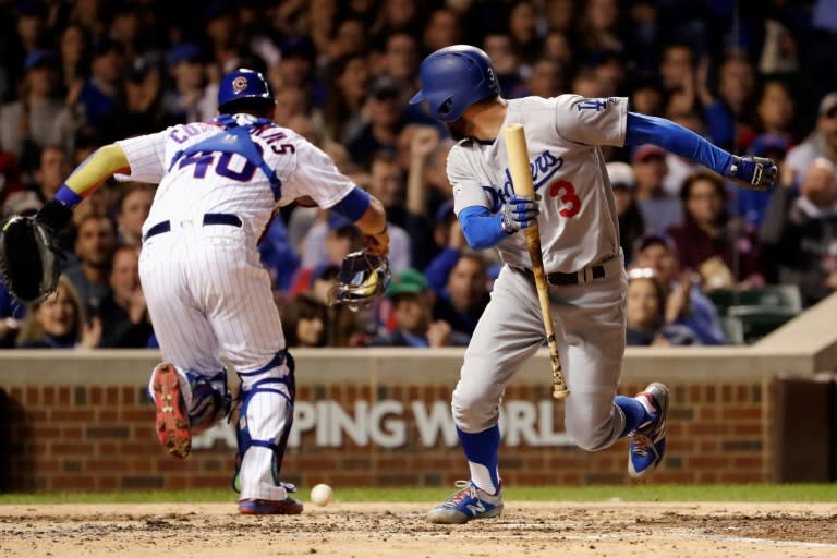 Chris Taylor (R) of the Los Angeles Dodgers attempts to reach first base as Willson Contreras of the Chicago Cubs chases after a dropped third strike in the fifth inning during game four of the NL Championship Series, in Chicago, on October 18, 2017