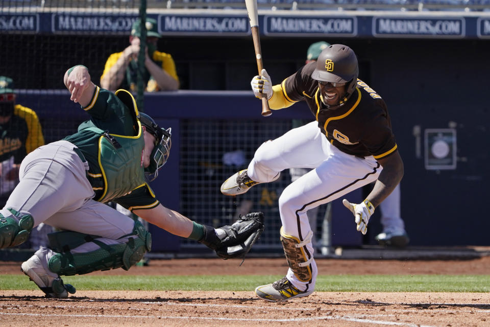 RETRANMISSION TO CORRECT LOCATION TO PEORIA - San Diego Padres' Jurickson Profar falls after being hit by a pitch in front of Oakland Athletics catcher Sean Murphy, left, in the first inning of a spring training baseball game Thursday, March 18, 2021, in Peoria, Ariz. (AP Photo/Sue Ogrocki)